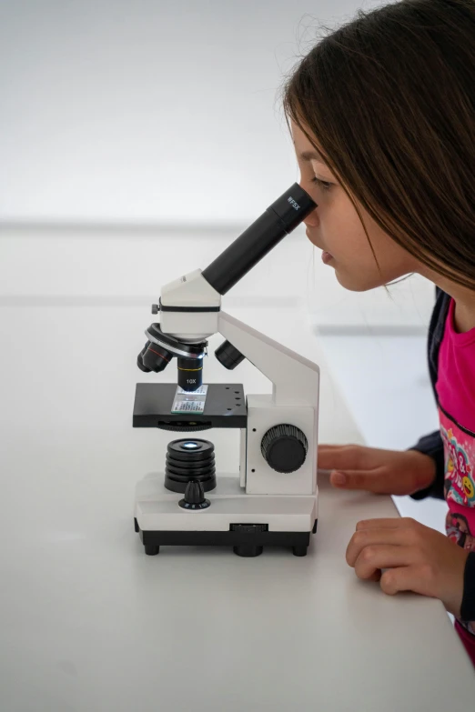 a girl looking through a microscope at a piece of food