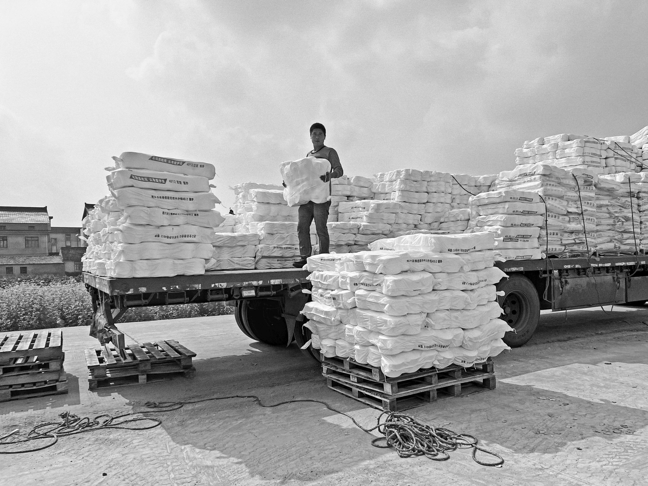 a man stands on a big truck loaded with sand bags