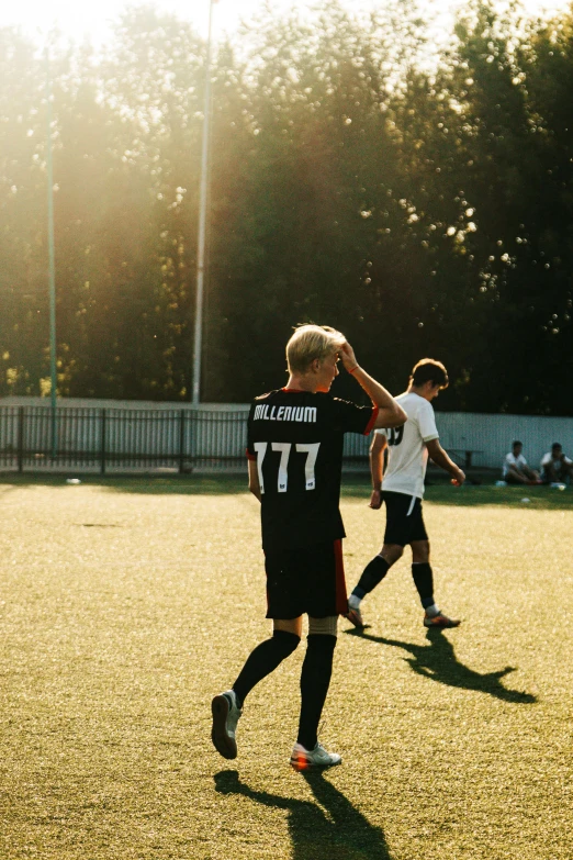 two men on the field playing soccer while other people watch