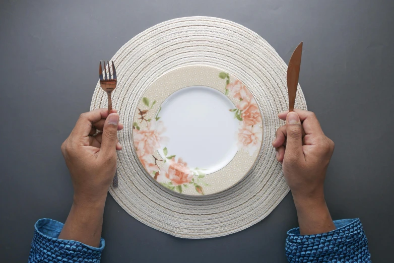 a person holding a fork and knife over a plate