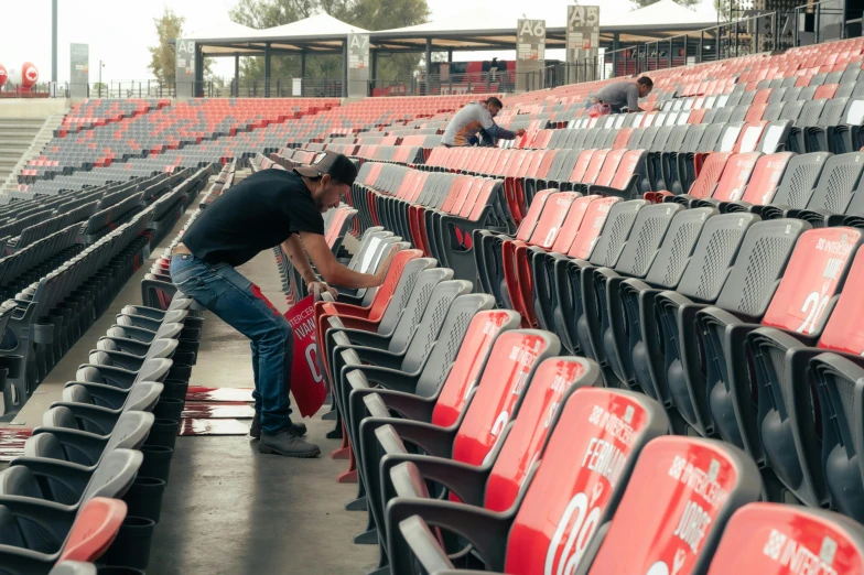 a man cleaning the seats of empty stadium seats