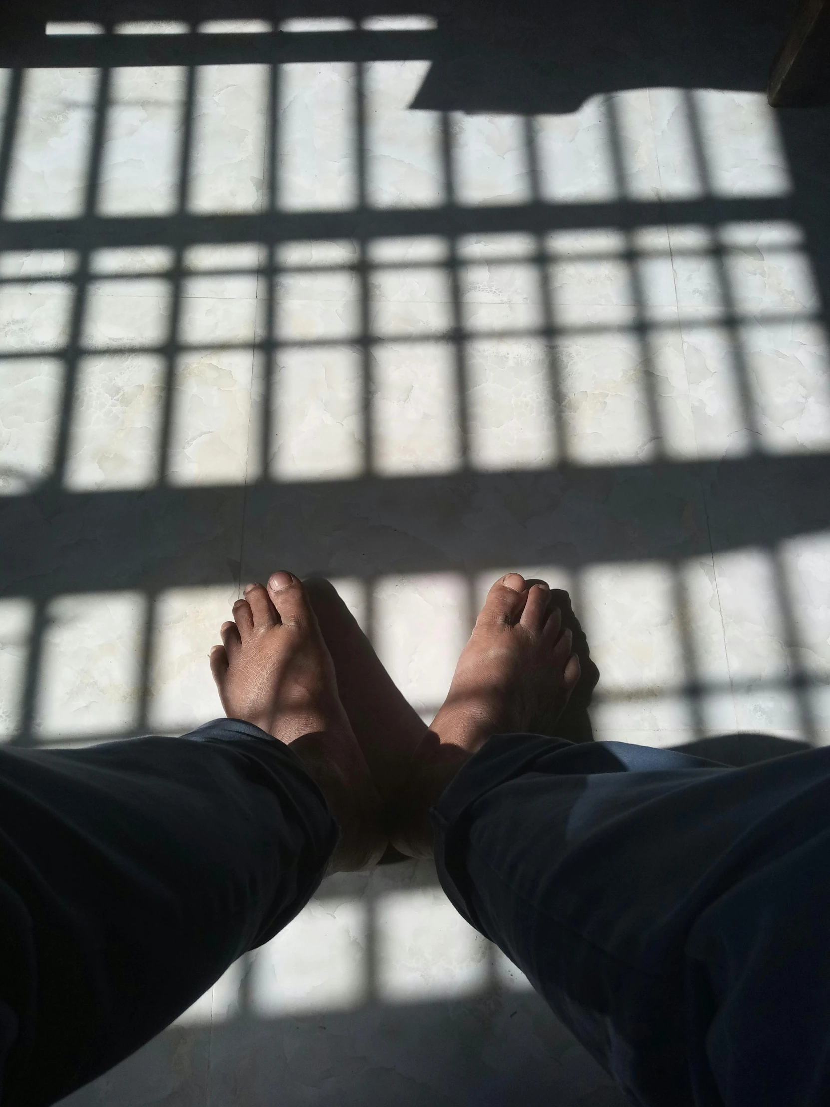 the feet of a person in front of window bars