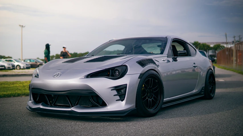 a silver and black sports car sits in front of some other cars