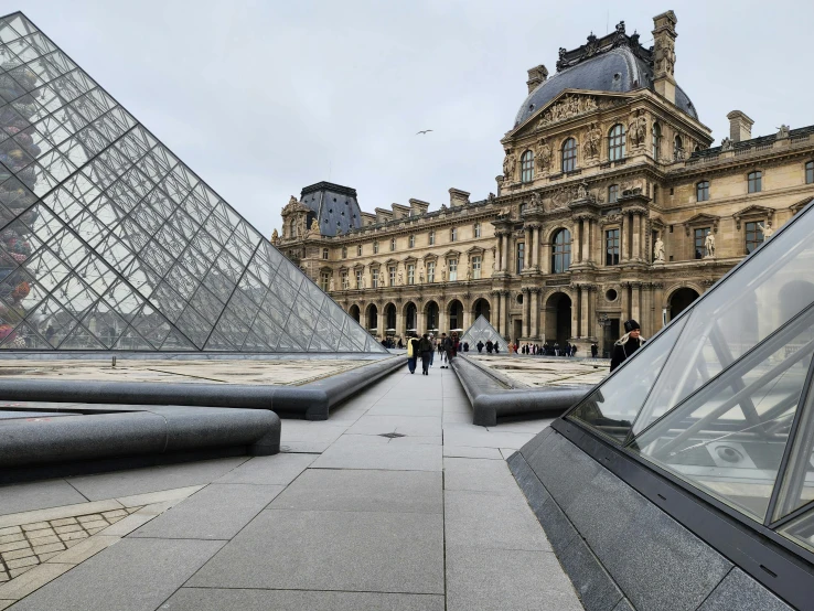 an outside plaza near a large building and pyramid