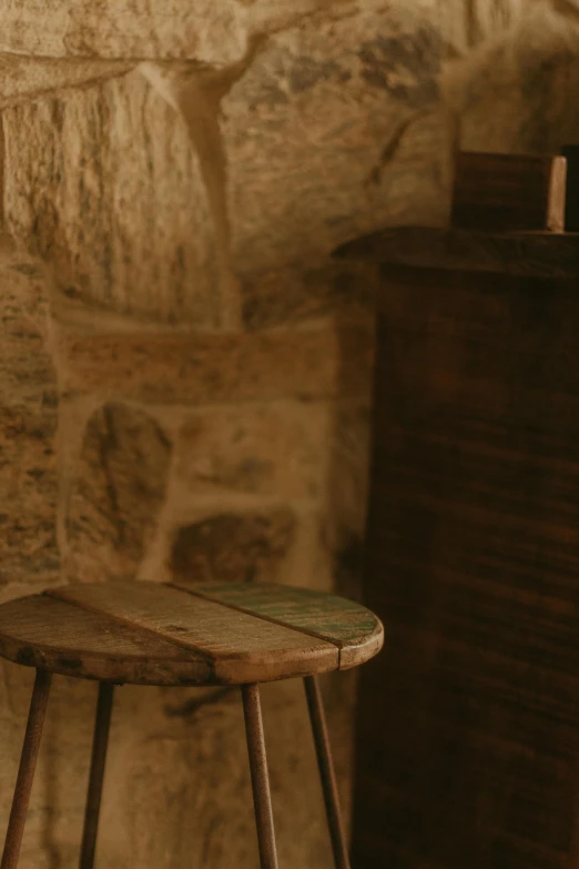 a small wooden stool next to a wall