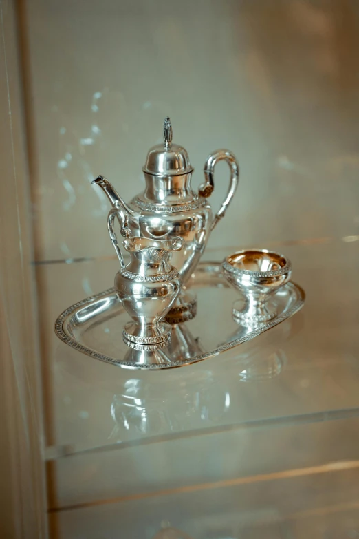 a silver teapot on display in a clear glass case