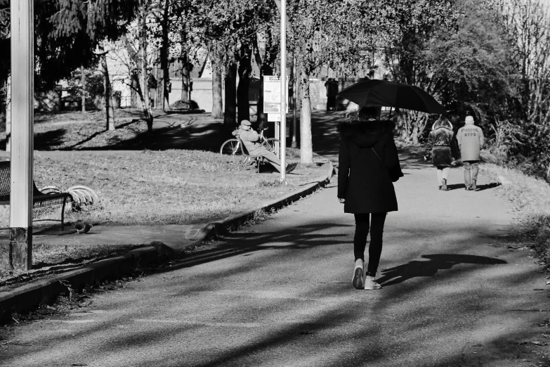 a woman is walking down the sidewalk with an umbrella