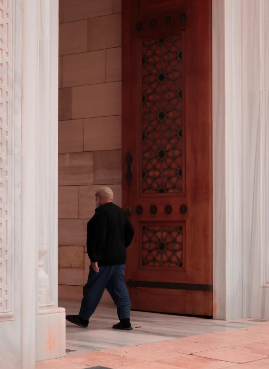 a man walking through an ornate doorway near a building