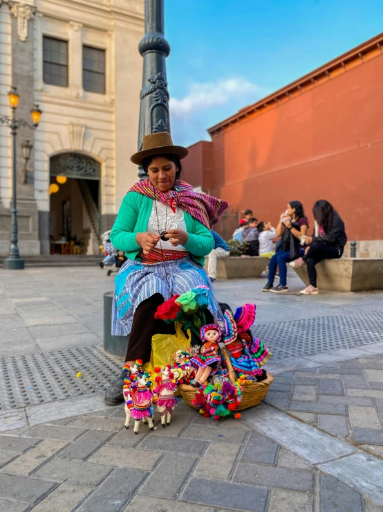 a woman in an elaborate dress sits on a brick sidewalk