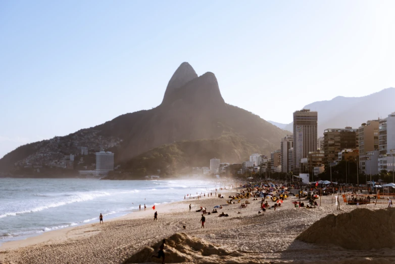 a crowded beach next to some very tall buildings