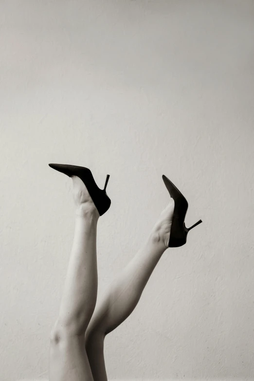 a woman standing on her legs holding up a pair of shoes