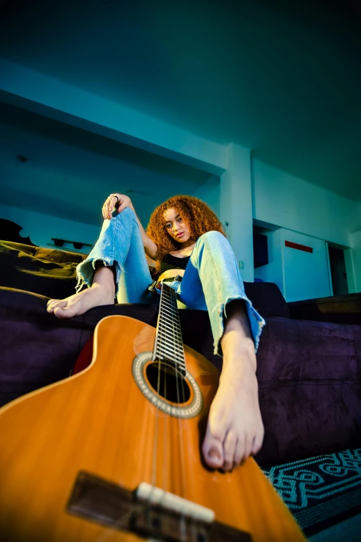 a girl laying on top of a purple couch playing the guitar