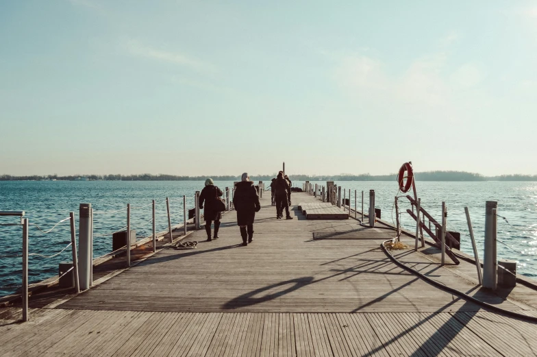 a long pier extending into the ocean with people walking along it