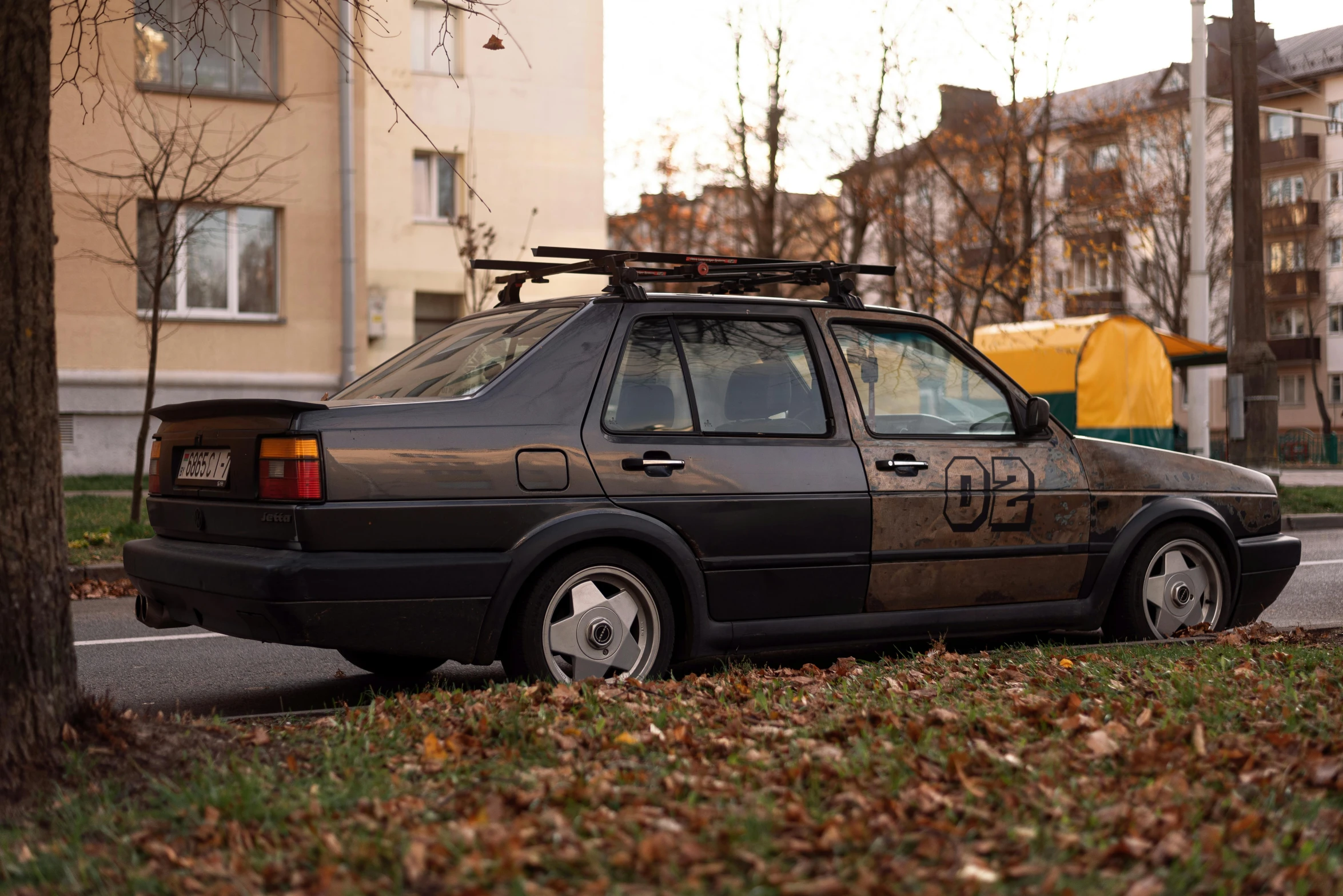 the car is parked on the curb next to a tree