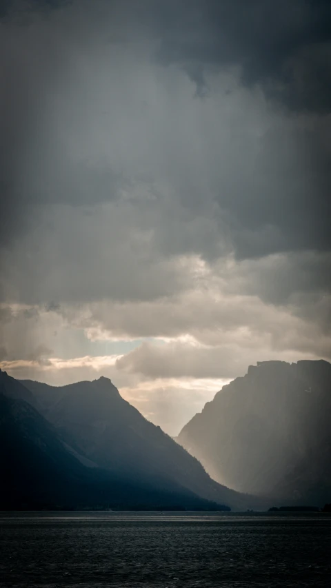 a sailboat that is on the water under a cloudy sky