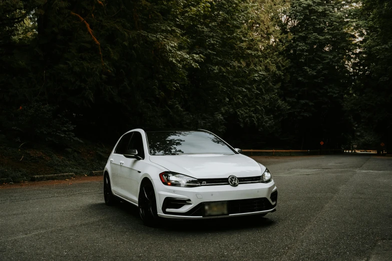 a white volkswagen in front of some trees