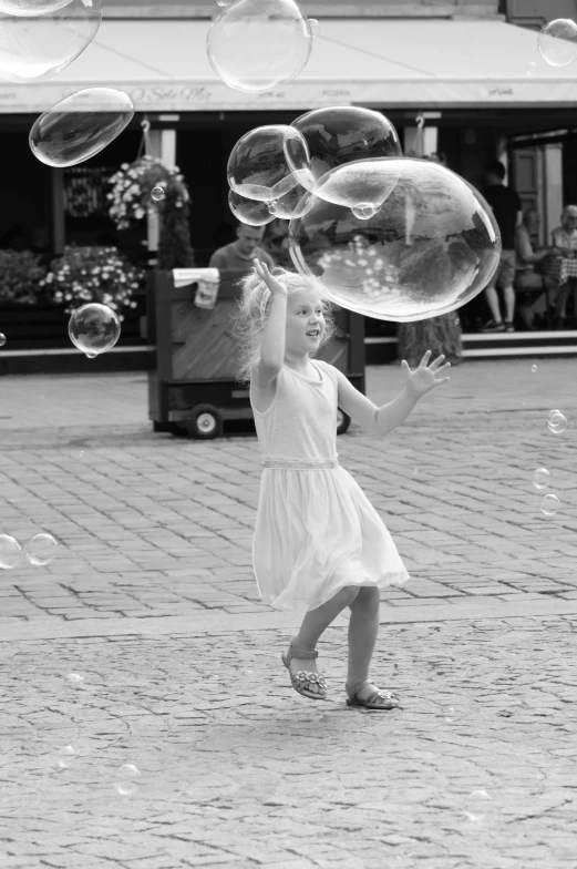 a girl in a dress is playing with bubbles on the street