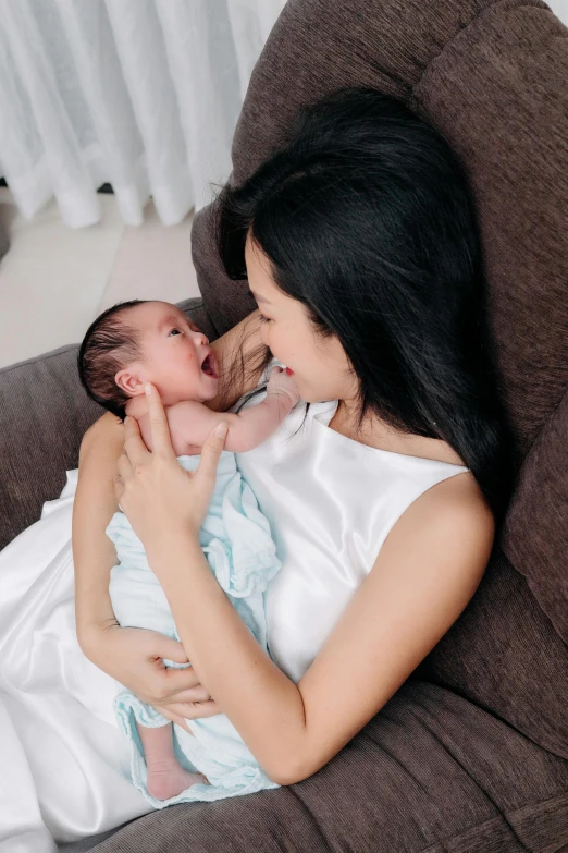 a woman and a baby laughing together on a chair