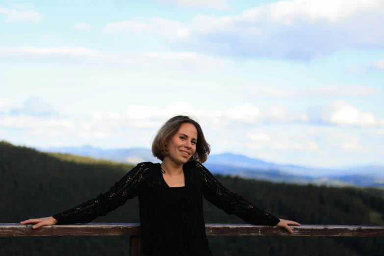 woman standing on fence with trees in the background