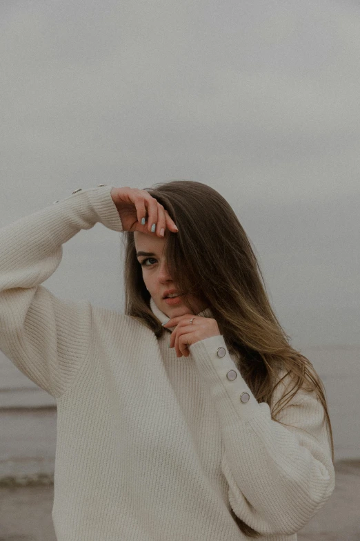 a woman with long hair is wearing a white sweater