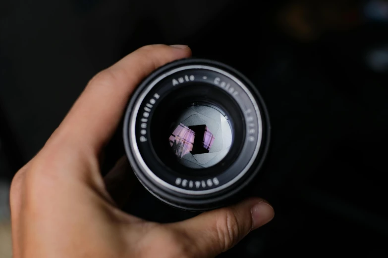 this is someones hand holding a small lens with it's reflection
