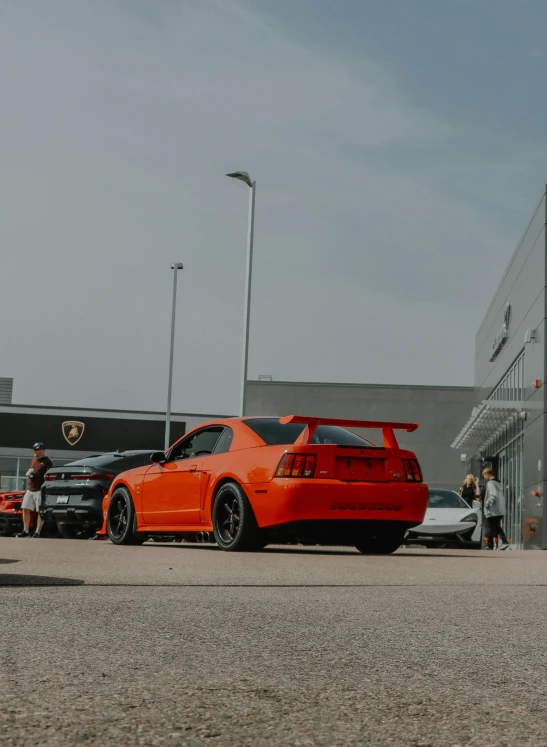 a bright orange car is parked near two other cars