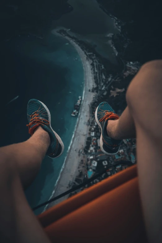 someone wearing blue sneakers looking over the water and taking a po with their legs