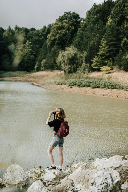 a person standing on top of a rock by a lake