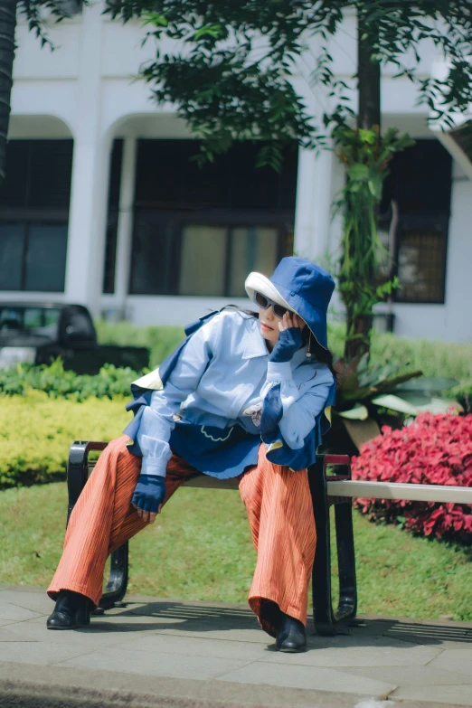 a woman sitting on a bench with a hat and blue jacket