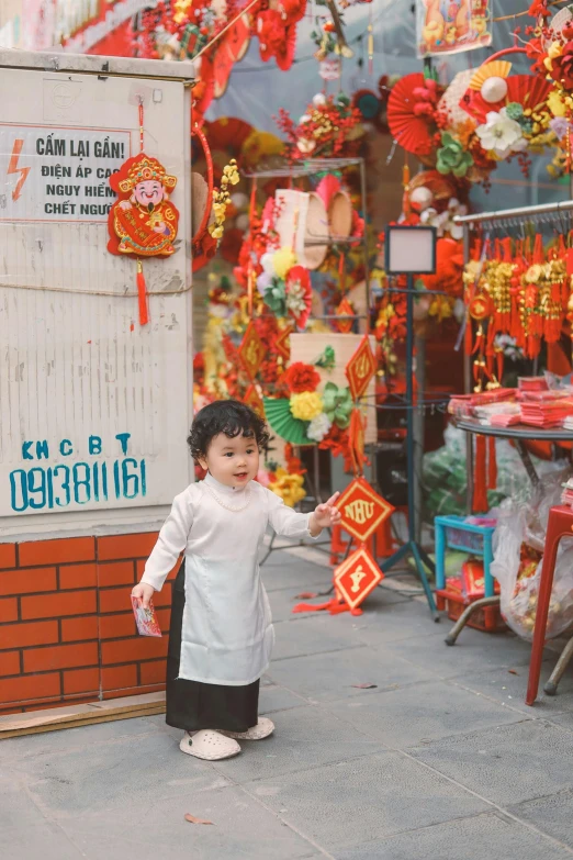 small child standing outside a store holding onto the string