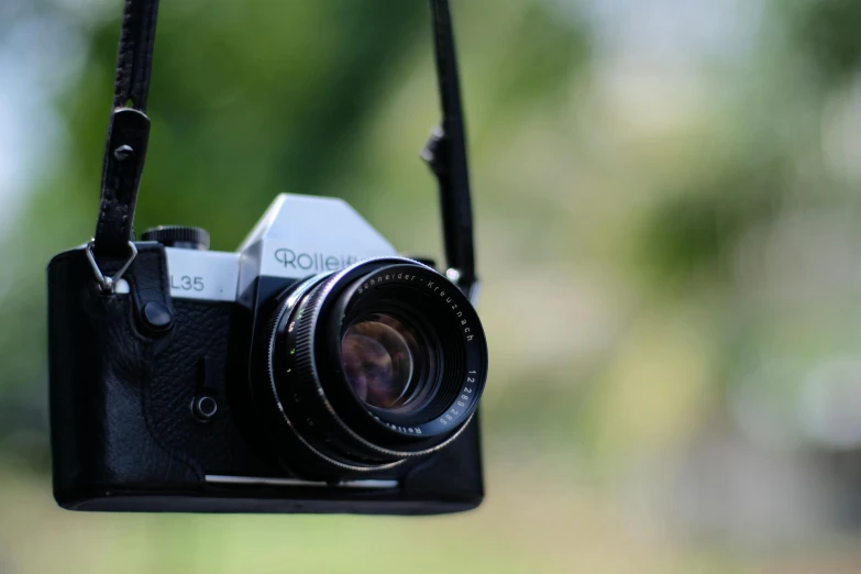 a camera attached to a strap with some blurry grass