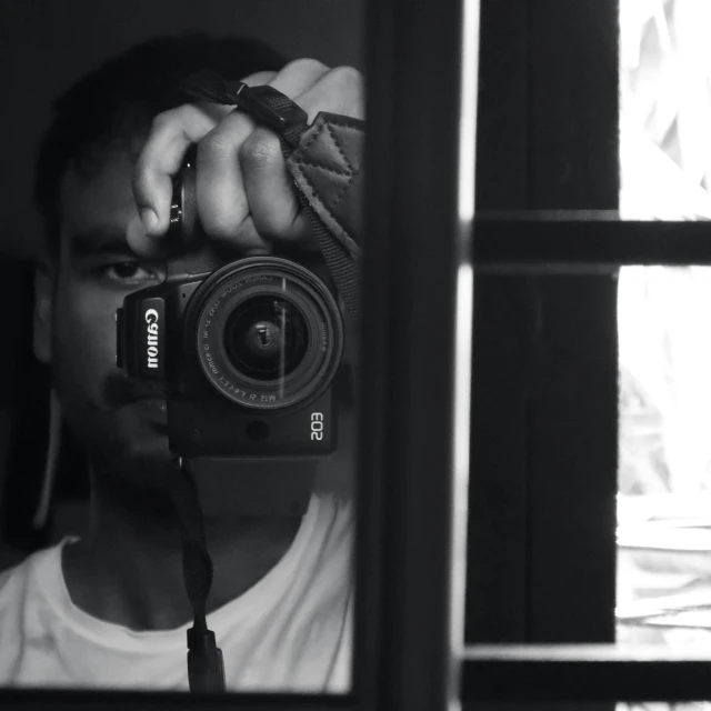 a man holding up his camera near some windows