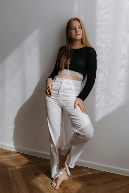 a woman in white pants is leaning against the wall