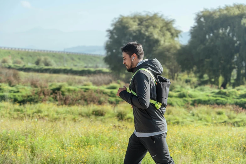 a man walking in a field wearing a backpack