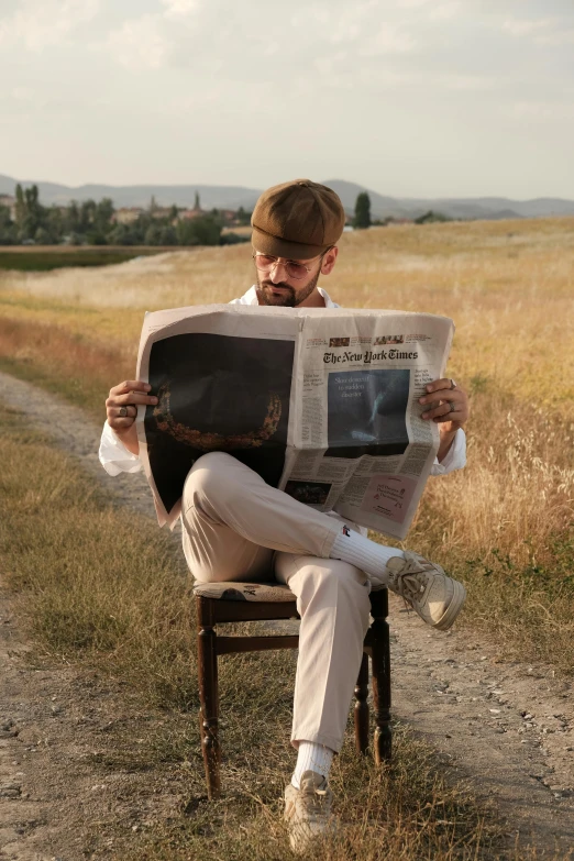 a man sits on a chair and reads the newspaper