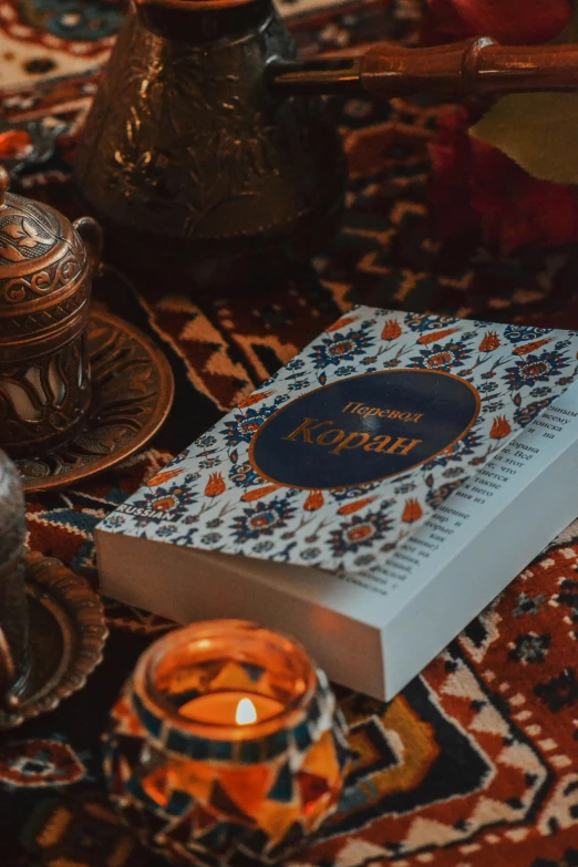 a book with a pattern sits on the ground surrounded by tea lights