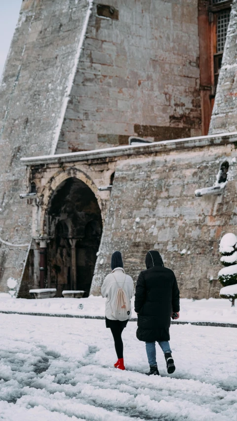 two people walking in front of an old castle