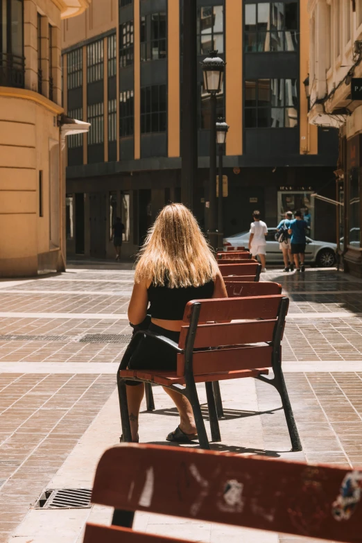 a person sitting on a wooden bench in a plaza