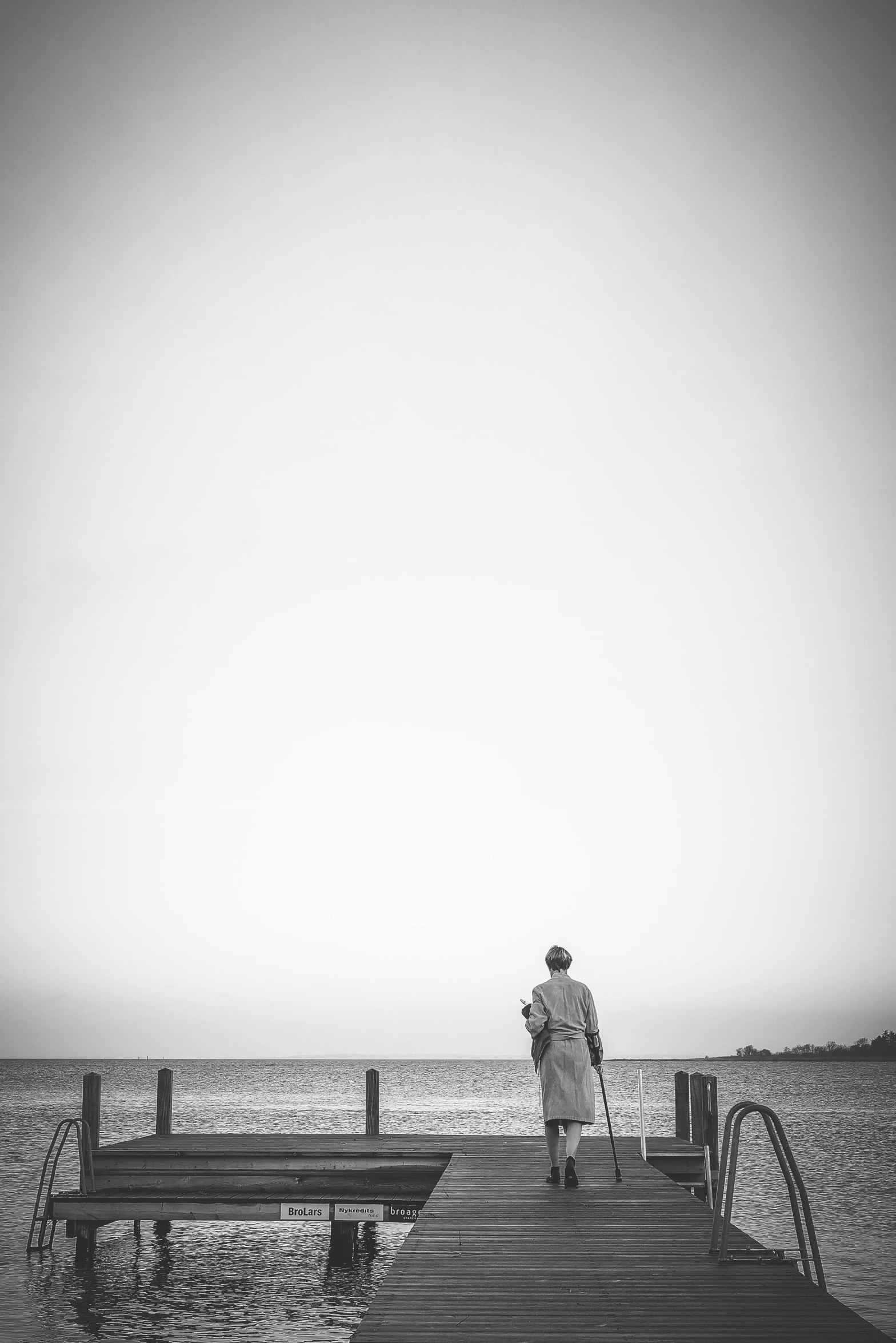 man is walking on a dock towards the ocean