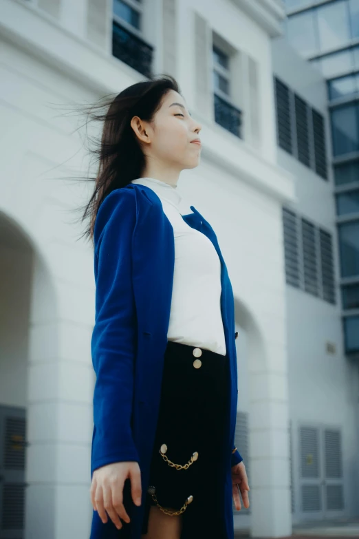 young asian woman looking upwards outside of a building