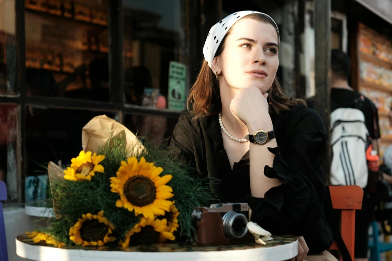 the woman sits by a table with flowers