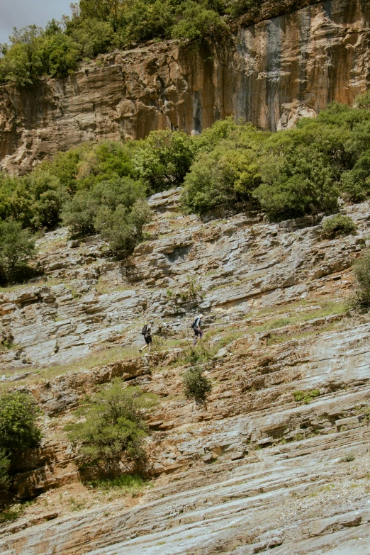 people are parasailing along the side of a cliff