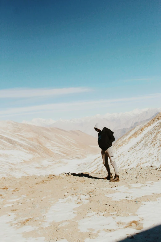 man with black backpack walking up the side of a mountain