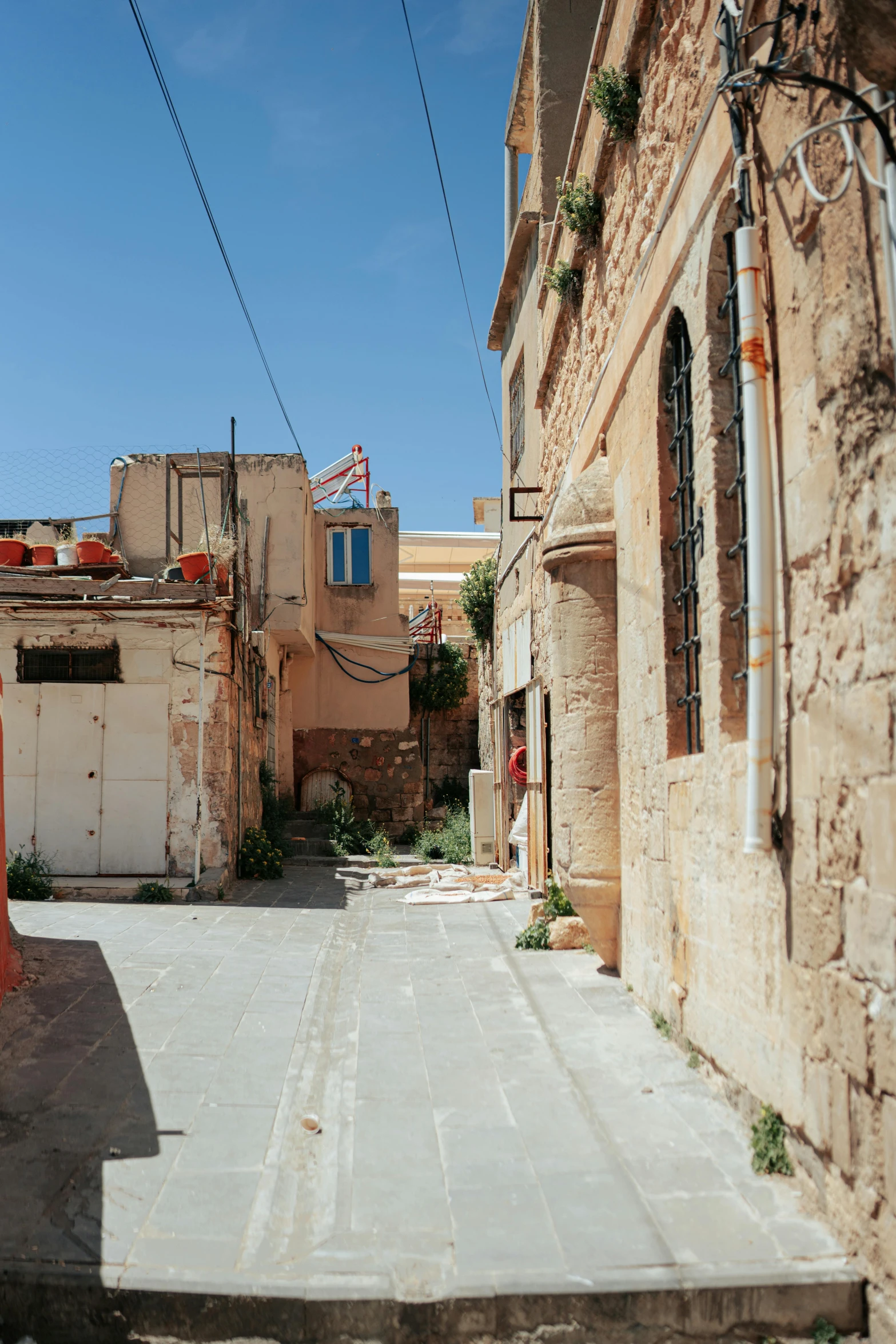 an alley way between some buildings with power lines hanging above