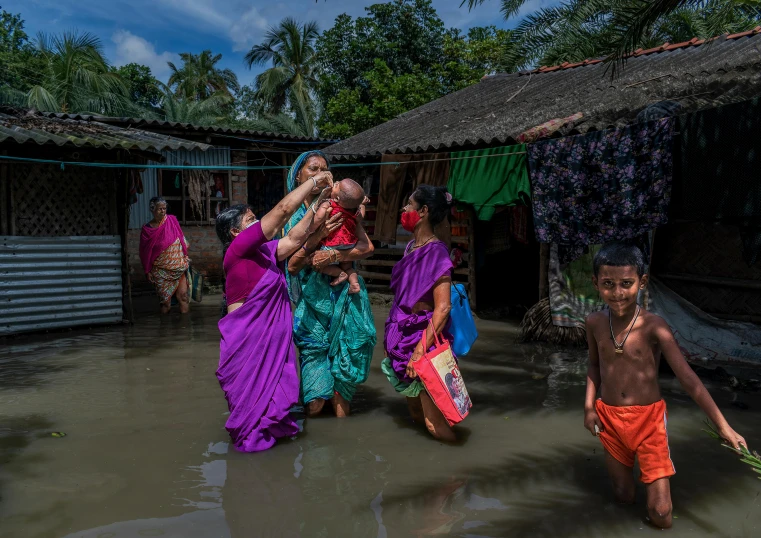 people in saris with orange shorts are walking in water