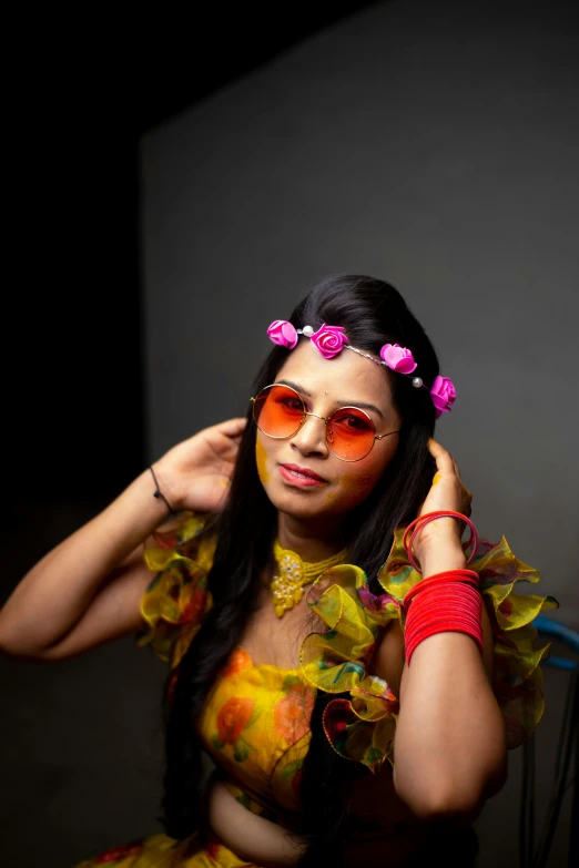 a girl with pink flowers in her hair and orange sun glasses