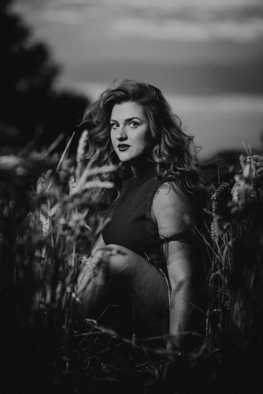 a woman kneeling in the grass, with her hand on her hip