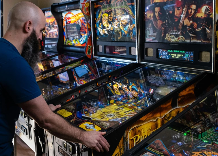 the man is looking through a case at the pinball game