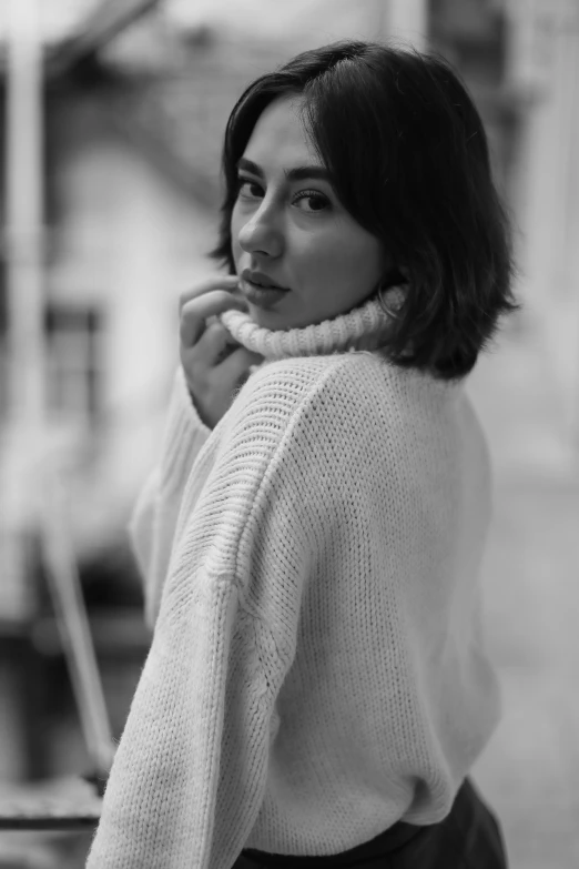 a woman wearing a turtle neck sweater poses in the street