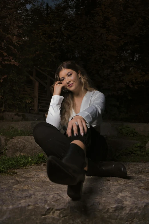 a young woman sitting on a rock while talking on a cell phone